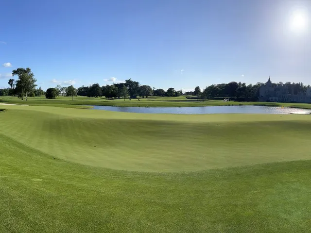A close view of a green and flagstick at Adare Manor, with the manor behind the hole.