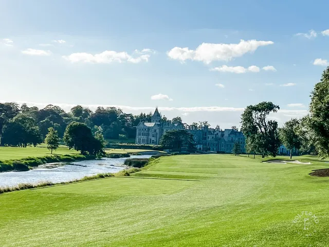 A green and flagstick at Adare Manor beside the water.