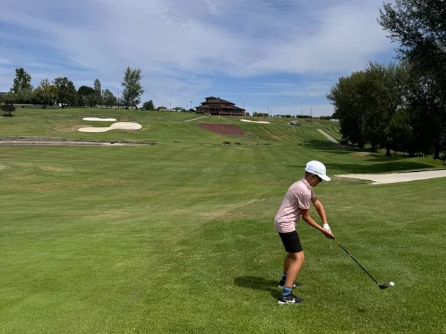 A fairway at Apple Tree lined with trees, running toward the mountains.