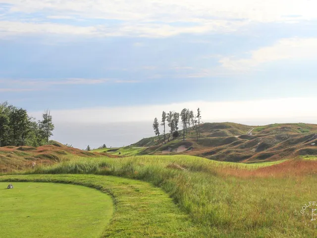 A golfer hitting a shot at Arcadia Bluffs, with the fairway and the lake ahead.