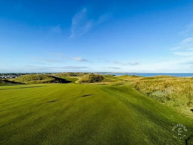 A golfer putting on a green on the Old Course, with the ocean beyond the hole.