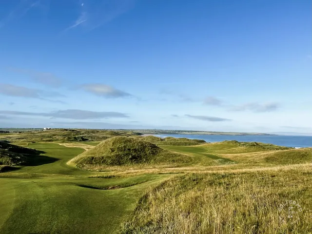A close view of a green and flagstick on the Old Course, with the Atlantic behind it.