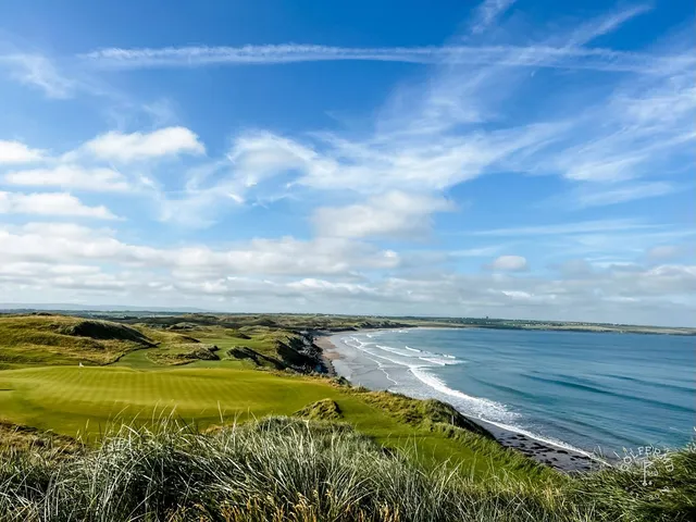 A fairway and green on the Old Course, with a bunker in the foreground and the ocean beyond.