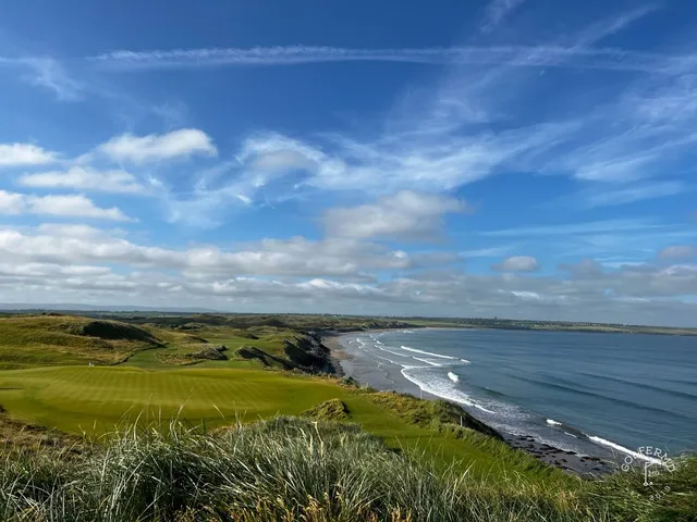 A wide fairway on the Old Course, with dunes on both sides and the water in the distance.