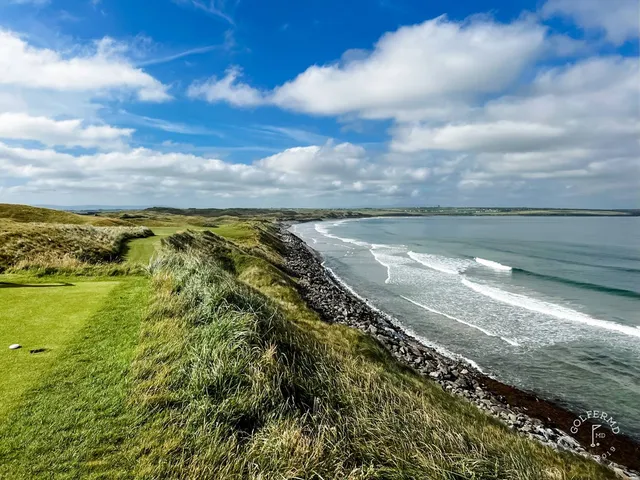 A group of golfers on the Old Course, with the ocean and the dunes behind them.