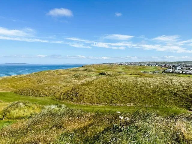 A wide view across the Old Course, with fairway, dunes, and the ocean.