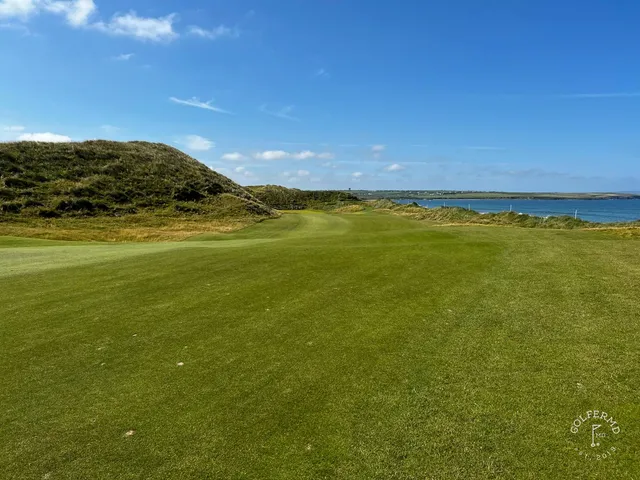 A green and flagstick on the Old Course, with a deep bunker in front and the water beyond.