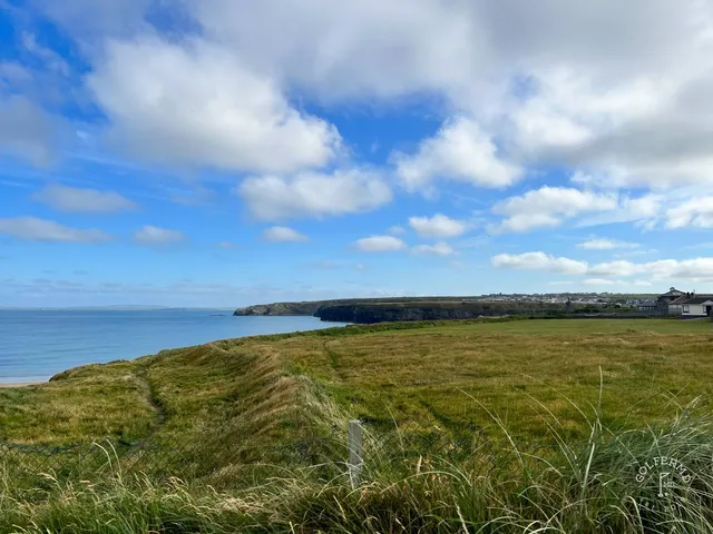 A green and flagstick on the Old Course, with a bunker short of the green and the ocean beyond.