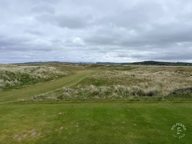 A green and flagstick on the Glashedy Links, with a bunker in front and the water behind the hole.