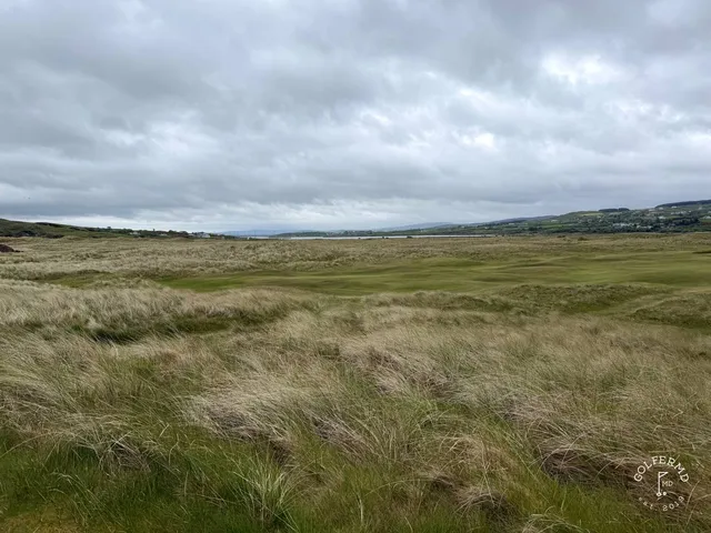 A golfer hitting a shot on the Glashedy Links, with the fairway and the ocean ahead.