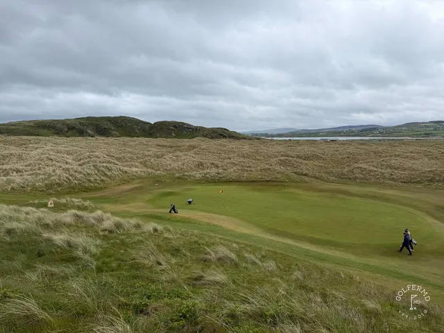 A green and flagstick on the Glashedy Links, seen from the fairway, with the ocean beyond.