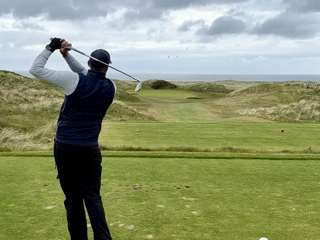 A fairway and green on the Glashedy Links, with a bunker in the foreground and the ocean beyond.