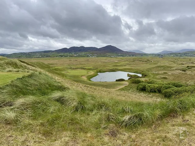 A close view of a flagstick on the Glashedy Links, with the Atlantic behind the green.