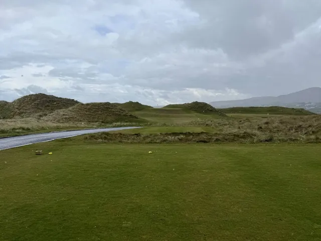 Golfers on a tee on the Old Links, with the course behind them.