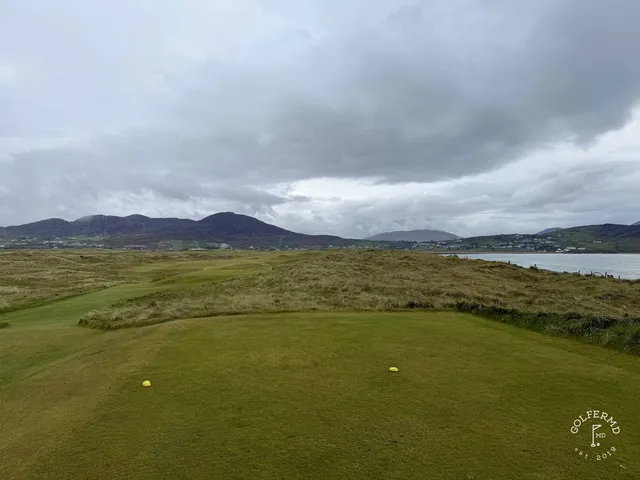 A close view of a green and flagstick on the Old Links, with the water behind it.