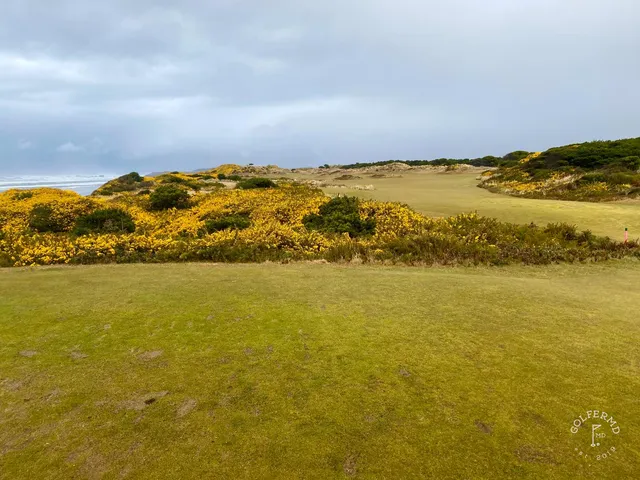 A green and flagstick at Bandon Dunes, with the Pacific behind the hole.