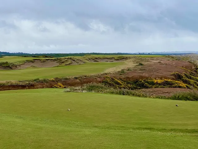 Golfers on a tee at Bandon Dunes, with the Pacific behind them.