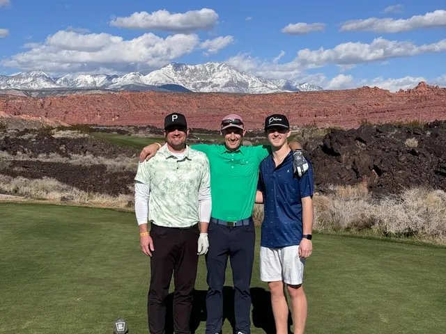 A green and flagstick at Black Desert, with lava rock around the green and the cliffs behind.