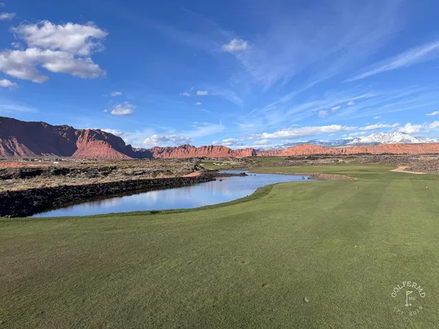 A wide view across Black Desert, with fairway, black rock, and the red cliffs.