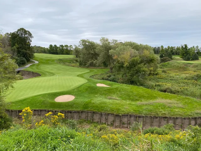 A fairway at Meadow Valleys lined with long grass, with trees in the distance.