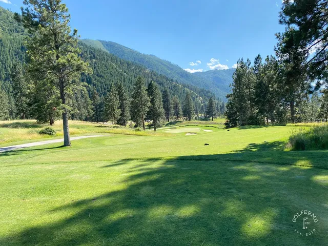 A green and flagstick at Canyon River, with a bunker in front and forest behind the hole.