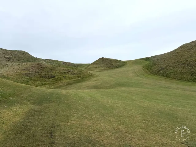 A close view of a green and flagstick at Carne, with the water behind it.