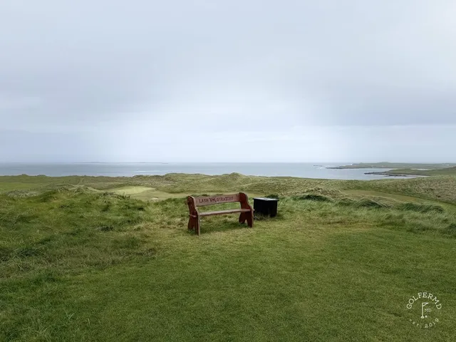 A fairway at Carne with a bunker along one side and the water ahead.