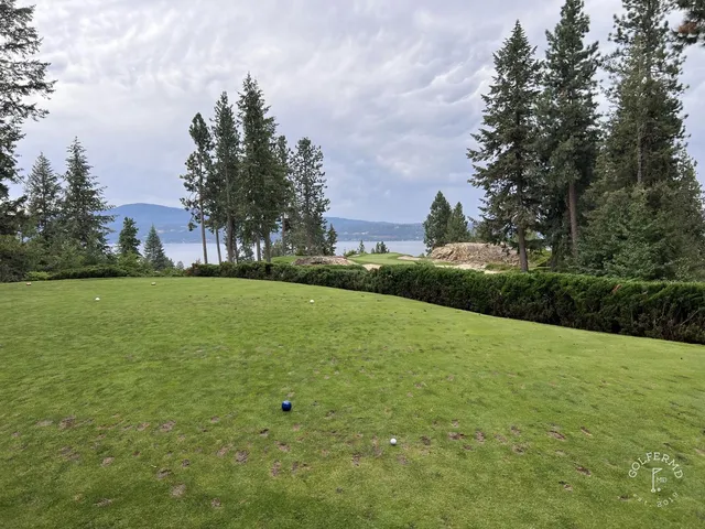 A green and flagstick at the resort course, seen from the fairway, with the water behind it.