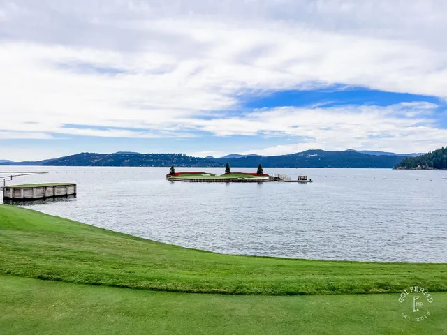 A fairway and green at the resort course, with a bunker and the lake beside the hole.