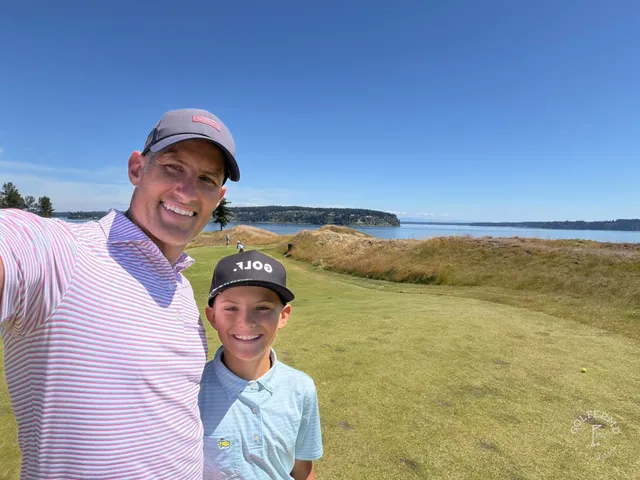 A golfer hitting a shot at Chambers Bay, with the fairway and the water ahead.