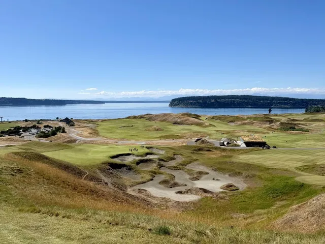 A fairway and green at Chambers Bay, with a bunker in the foreground and the sound beyond.
