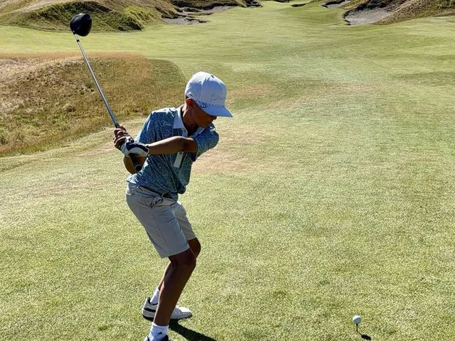 A green and flagstick at Chambers Bay, seen from a rise, with the sound behind the hole.