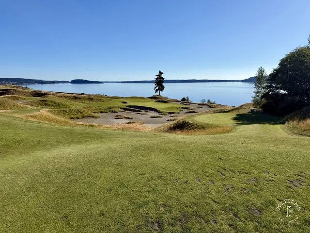 A green and flagstick at Chambers Bay, with a bunker in front and the sound beyond.