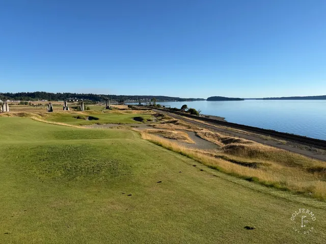 A close view of a flagstick at Chambers Bay, with the water behind the green.