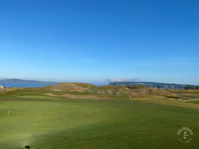 A group of golfers at Chambers Bay, with the dunes and the water behind them.