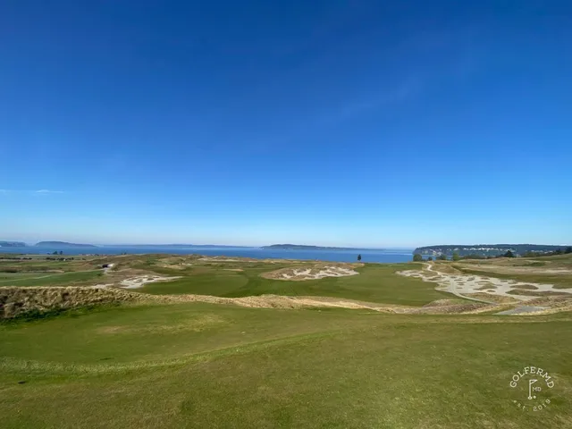 A golfer hitting a shot at Chambers Bay, with the sandy fairway and the sound ahead.