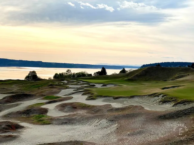 Golfers on a tee at Chambers Bay, with the dunes and the water behind them.