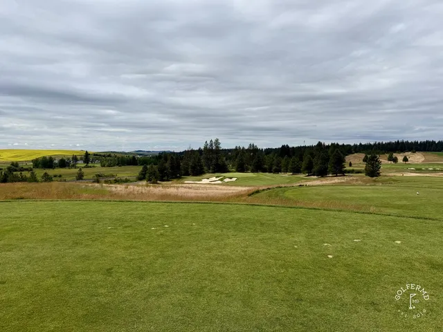 A fairway at Circling Raven with a bunker along the right and pines beyond.