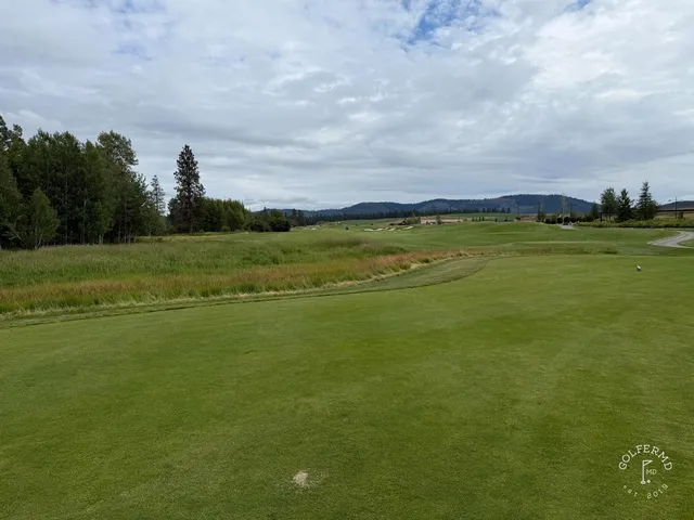 A fairway at Circling Raven with a bunker in the foreground and pines on the horizon.