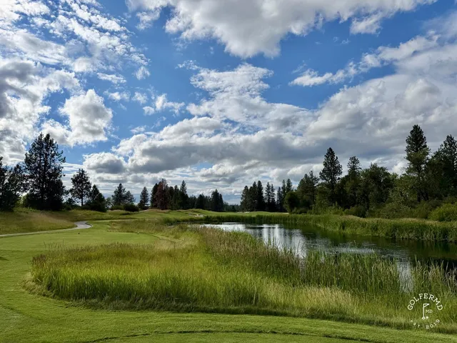 A group posing for a photo at Circling Raven, with the course and pines behind them.