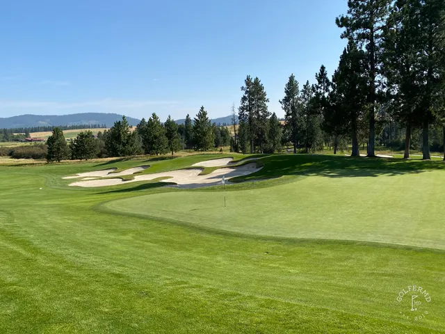 A fairway and bunker at Circling Raven, with the green tucked by the trees.