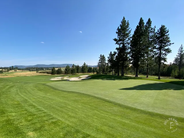 A green and flagstick at Circling Raven, seen across the fairway.