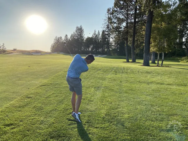 A close view of a green and flagstick at Circling Raven, surrounded by pine trees.
