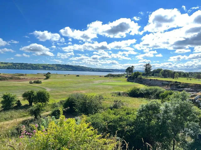 A green and flagstick at Cork Golf Club beside the estuary, with the hills beyond.
