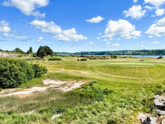A close view of a flagstick at Cork Golf Club, with the water behind the green.