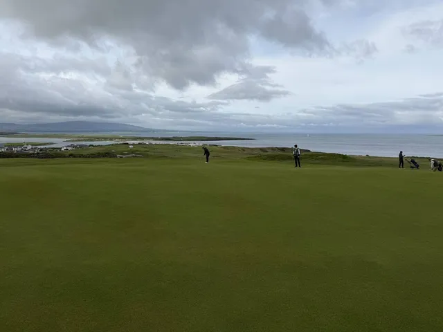 Golfers on a tee at County Sligo, with the Atlantic and the mountain behind them.