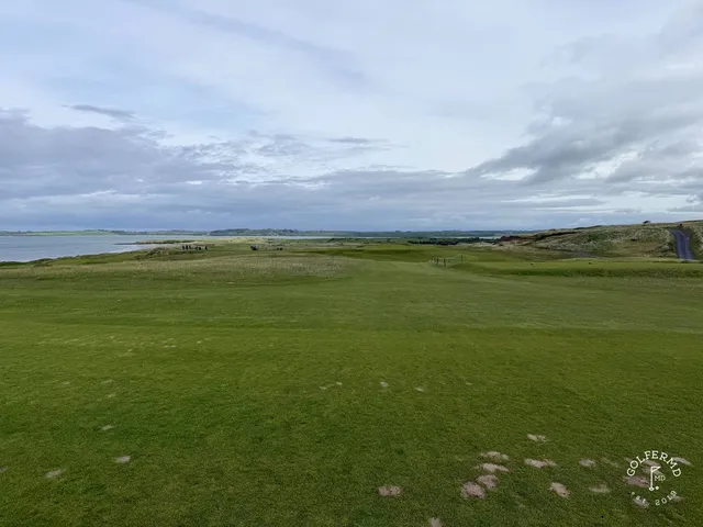 A golfer putting on a green at County Sligo, with the ocean beyond the hole.