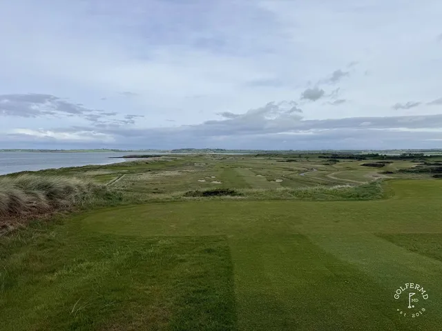 A close view of a green and flagstick at Rosses Point, with the water behind it.