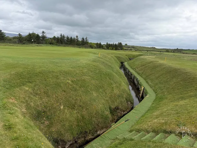 A fairway at Rosses Point with a bunker along one side and the water ahead.