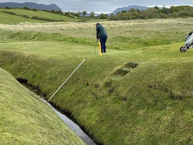 A green and flagstick at County Sligo, seen from a rise, with the mountain beyond.